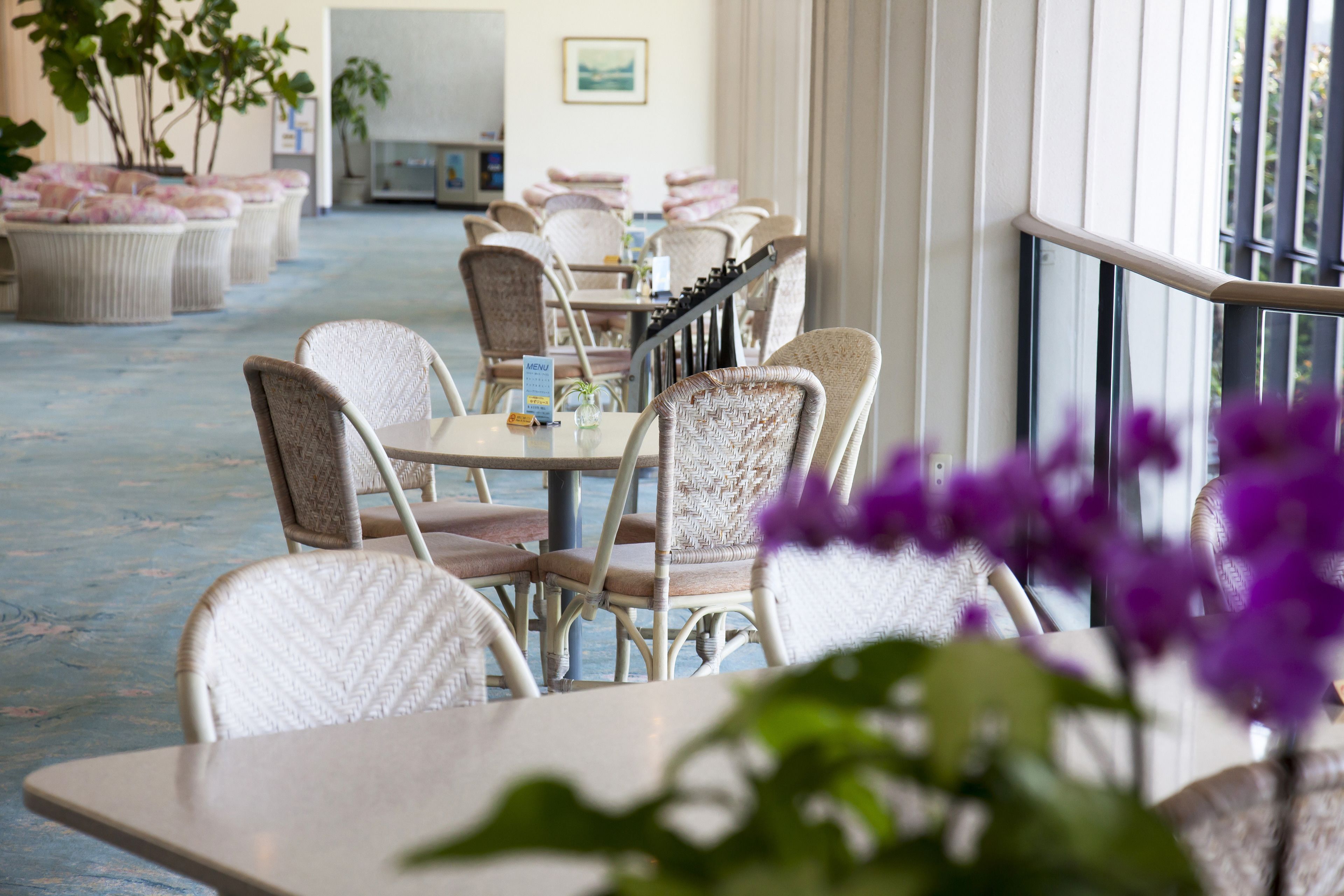A restaurant with wicker furniture and a view of the sea.