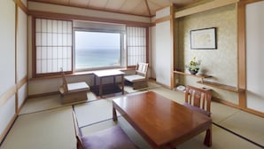 A traditional Japanese room with tatami flooring, a wooden table, and a view of the sea through shoji screens.