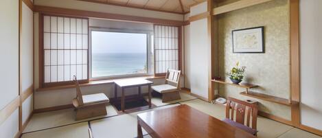 Ein traditioneller japanischer Raum mit Tatami-Böden, einem Holztisch und Meerblick durch Shoji-Schirme.
