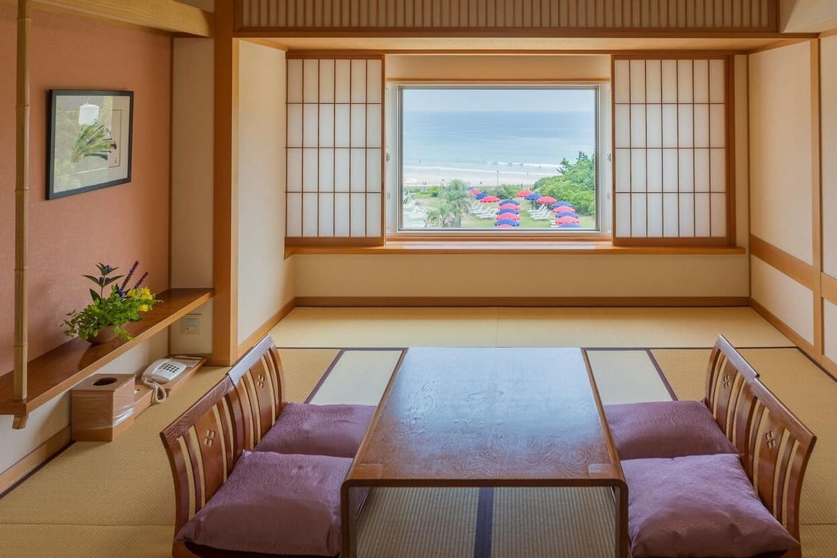 Una habitación japonesa tradicional con suelo de tatami, una mesa baja y paneles shoji.