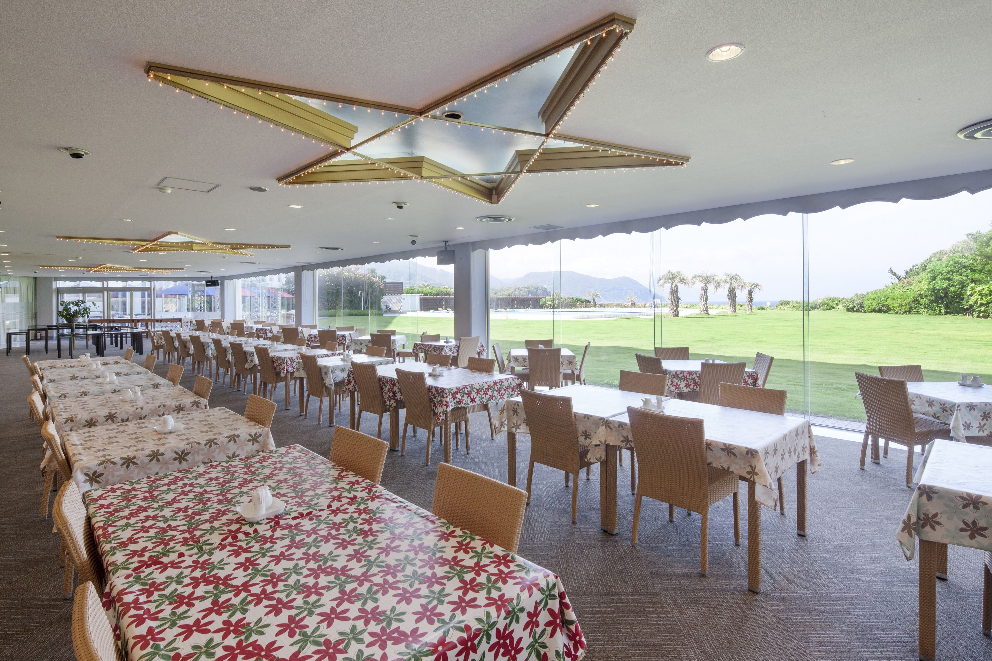 Un comedor amplio con varias mesas y sillas, grandes ventanales que dan a un campo de golf.
