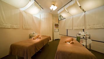 A room with two beds, a small table with toiletries, and a cabinet.