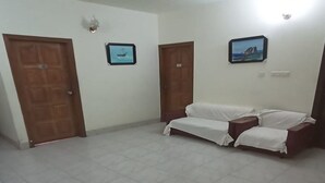 A room with a ceiling fan, two doors, a bed with white bedding, and two framed pictures on the wall. - Hotel Skylink (Dhaka)