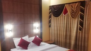 A hotel room with a large bed, two bedside lamps, a headboard, and a curtain with a pattern. - Hotel Skylink (Dhaka)