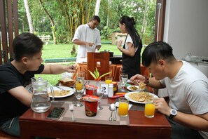 Uma mesa de jantar com pratos de comida, copos de suco de laranja e um jarro de água.