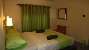 A hotel room with a bed, a nightstand, a mirror, and a green curtain. - Green Banana Mirissa (Mirissa)
