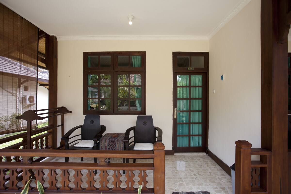 A room with two chairs, a small table, and a wooden bench.