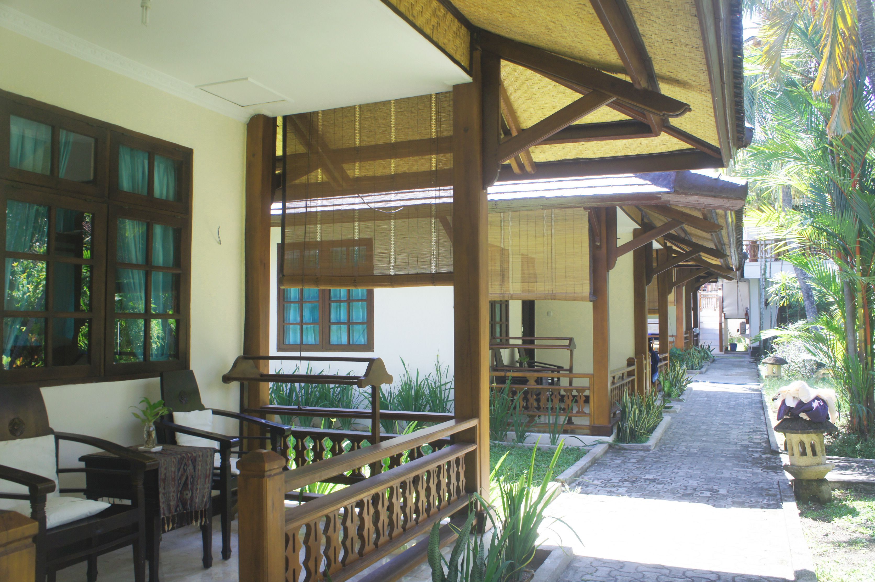 A covered outdoor seating area with wooden furniture and a thatched roof.