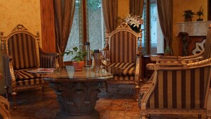 Una habitación con sillas tapizadas a rayas, una mesa con superficie de vidrio y un jarrón decorativo con flores.