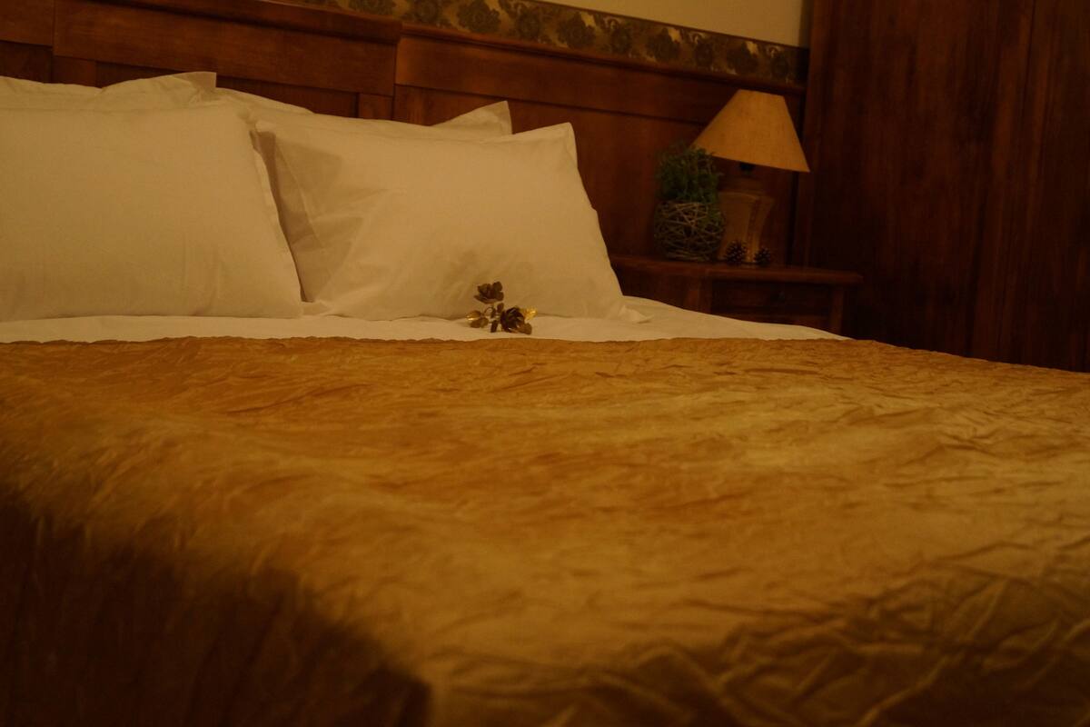 A bed with a wooden headboard, white pillows, and a decorative item on the nightstand.