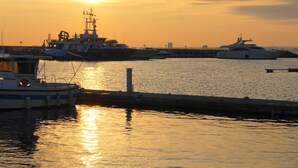 Un puerto deportivo con varias embarcaciones amarradas en un muelle al atardecer.