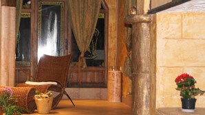 Un hall acogedor con un mostrador de recepción de madera, sillas de mimbre, una planta en maceta y un cuadro grande en la pared.