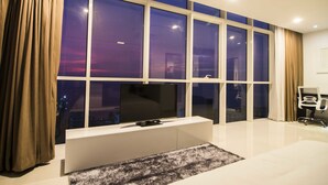 Ein modernes Wohnzimmer mit großem Fenster, einem Flachbildfernseher, einer weißen Unterhaltungsanlage und einem kleinen Sofa.