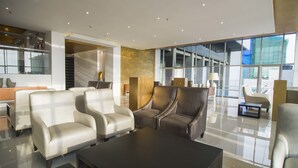 Eine moderne Lobby mit Ledersesseln, einem dunklen Couchtisch und großen Fenstern mit Blick nach außen.