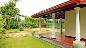 A covered outdoor area with a red roof, white columns, and a paved walkway. - Villa Thotiya (Aluthgama)