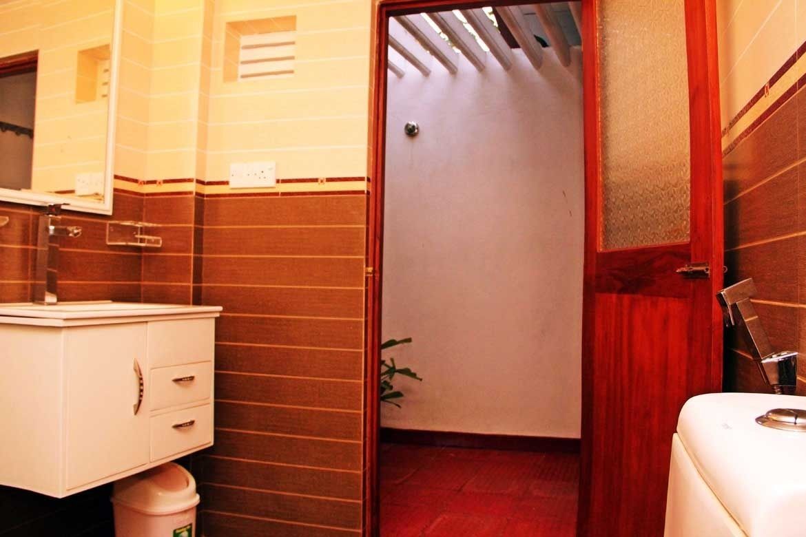 Un baño con lavamanos blanco, espejo y armario, cortina de ducha roja y retrete blanco.