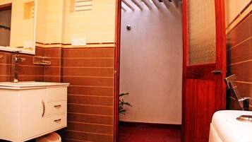 Un baño con lavamanos blanco, espejo y armario, cortina de ducha roja y retrete blanco.