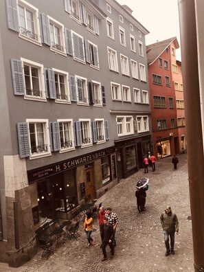 Eine Kopfsteinpflasterstraße mit Gebäuden im traditionellen europäischen Stil, darunter Fensterläden und Balkone.