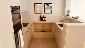 A modern kitchen with a built-in oven, two framed artworks, a wine rack with bottles, and a black wire basket on the countertop. - Zürich Niederdorf - Grossmünster (Zürich)