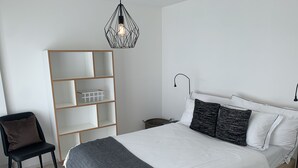 A bedroom with a bed, a chair, a shelving unit, and a pendant light. - Zürich Niederdorf - Grossmünster (Zürich)