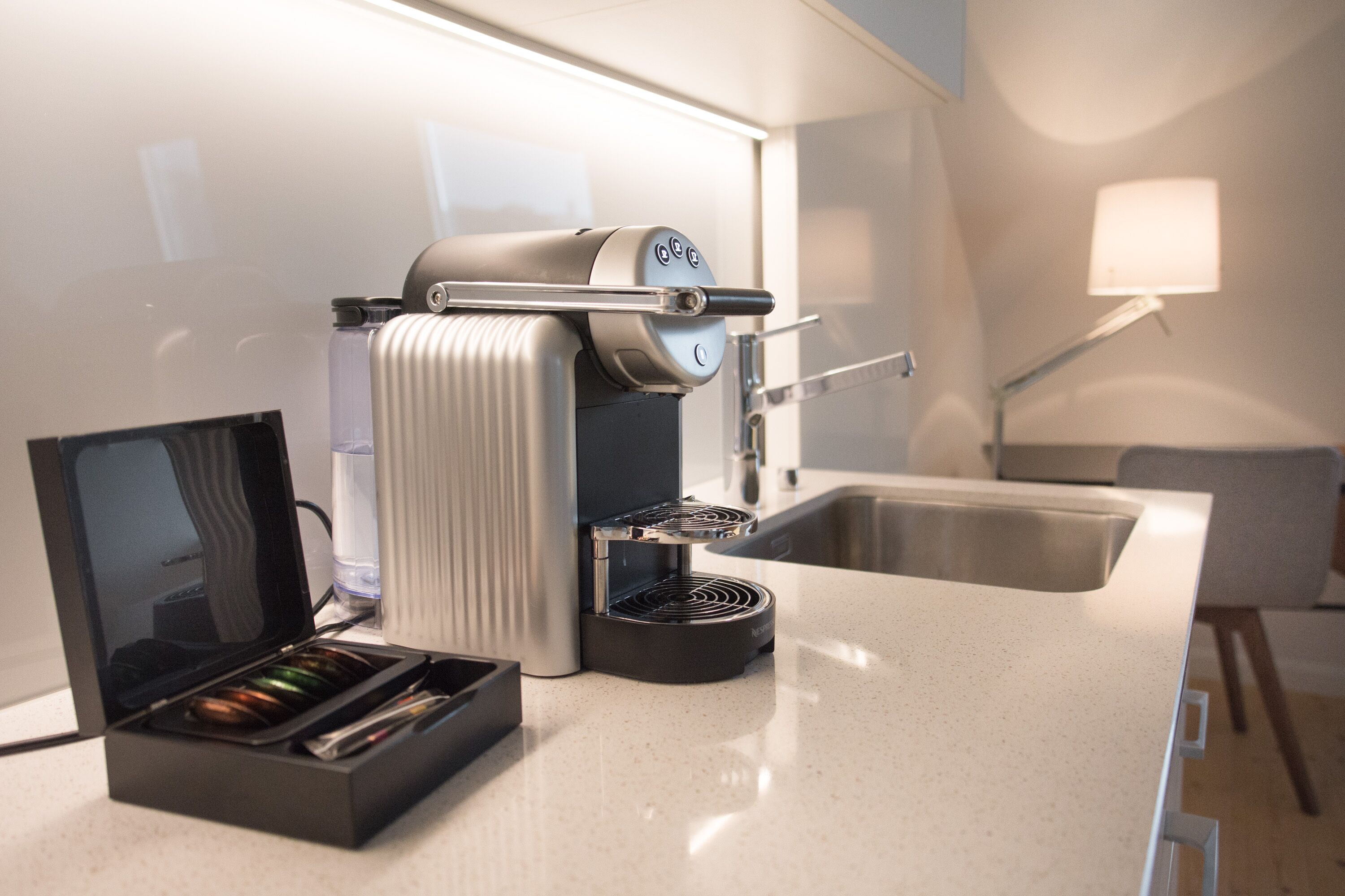 Una cocina moderna con una máquina de espresso integrada, un molinillo de café y un lavamanos.