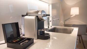 Una cocina moderna con una máquina de espresso integrada, un molinillo de café y un lavamanos.