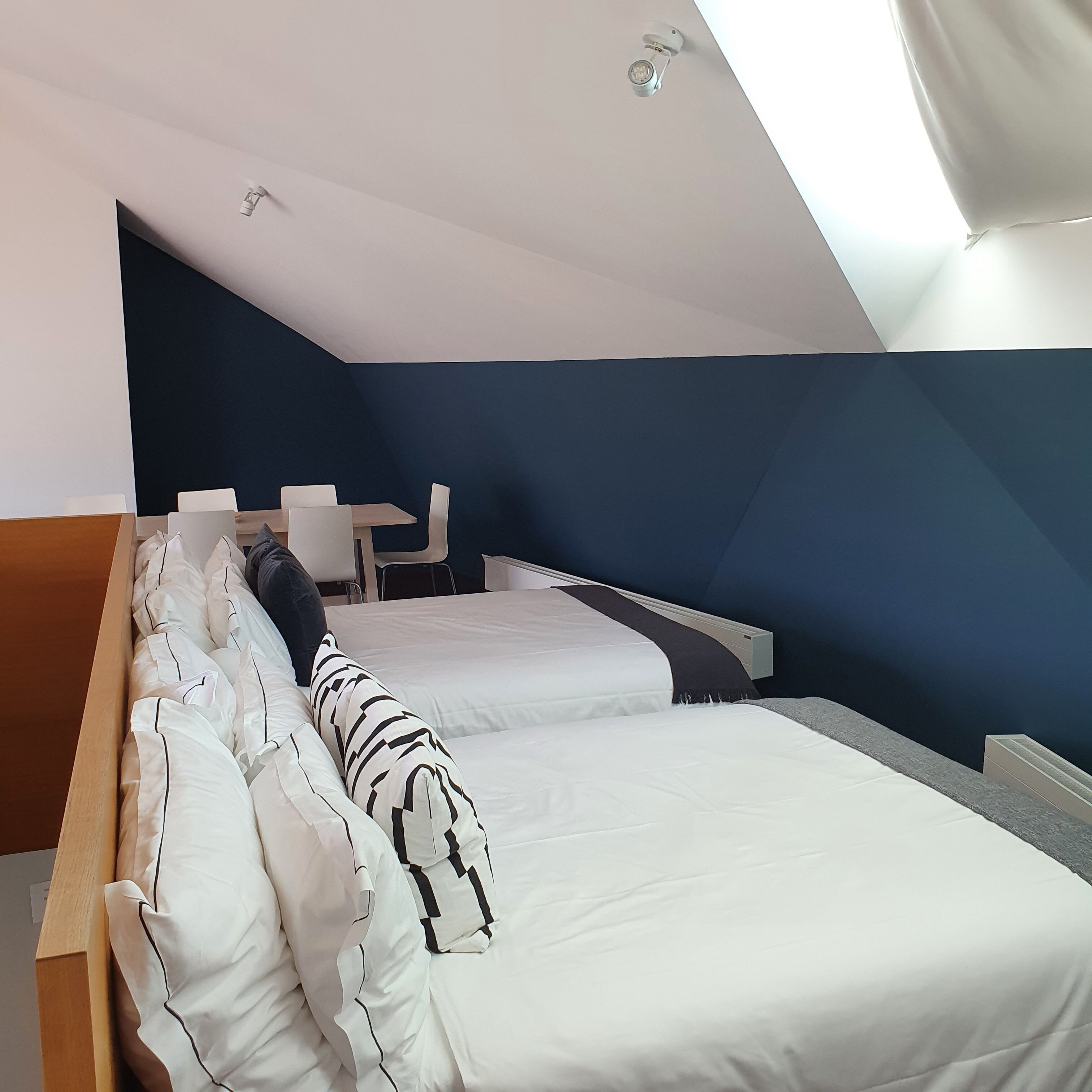 Ein modernes Schlafzimmer mit zwei Betten, einem Schreibtisch und einem Stuhl.