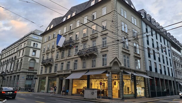 A historic building with multiple stories, large windows, and a prominent flag. - Top city center Lion Monument (Lucerne)