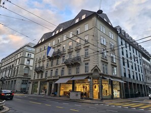 Un edificio histórico de varios pisos, con amplias ventanas y una bandera destacada.