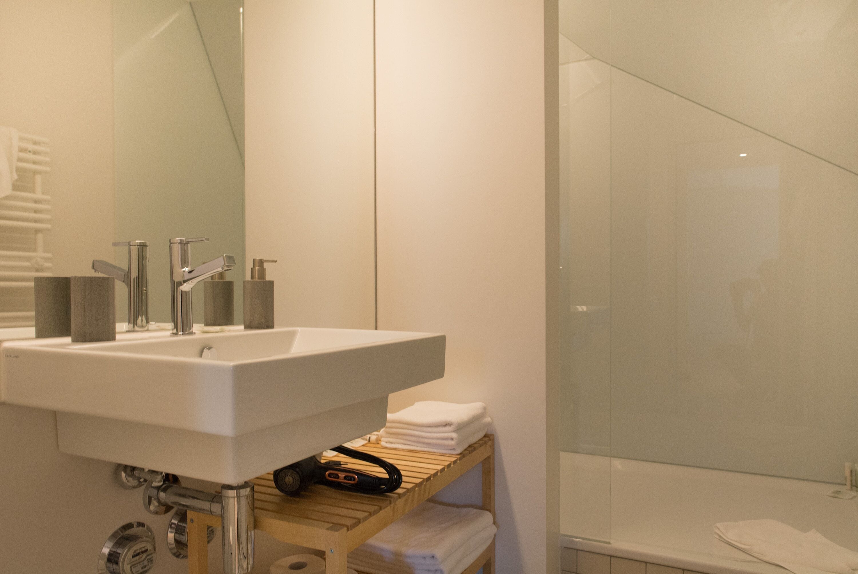 Une salle de bain moderne avec un lavabo blanc, un miroir et une cabine de douche en verre.