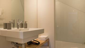 Une salle de bain moderne avec un lavabo blanc, un miroir et une cabine de douche en verre.