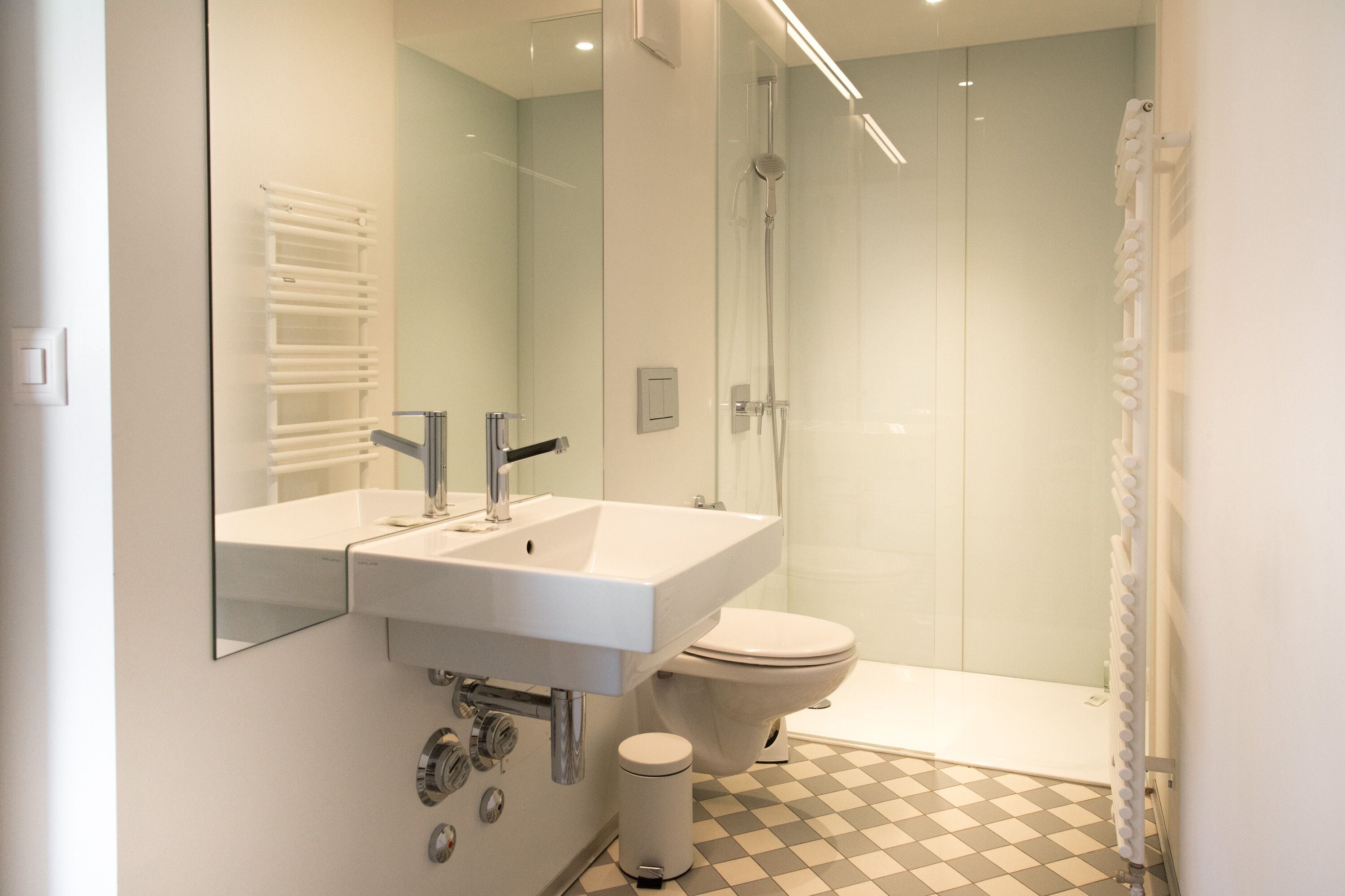 A modern bathroom with a white sink, mirror, and toilet.