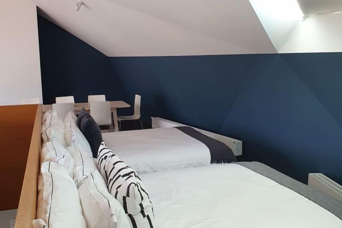 A modern hotel room with two beds, a desk, and a chair.