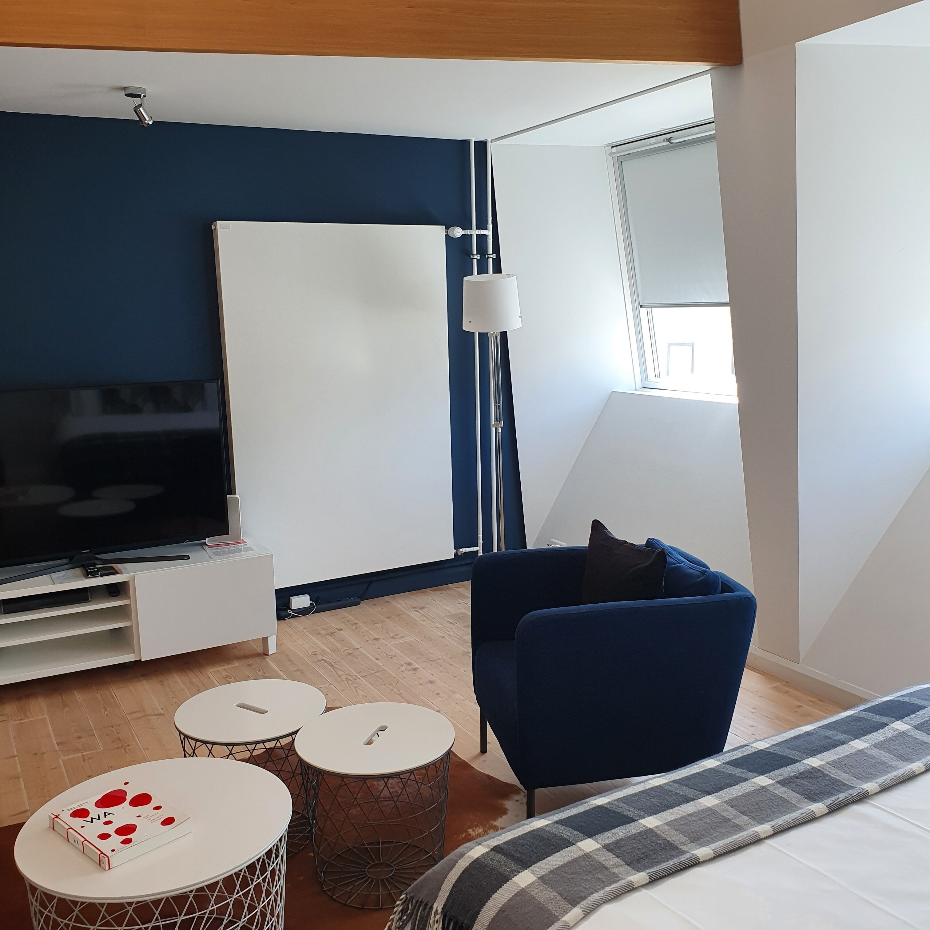 Una sala de estar moderna con un televisor de pantalla plana grande, un sofá azul y una mesita de centro pequeña.