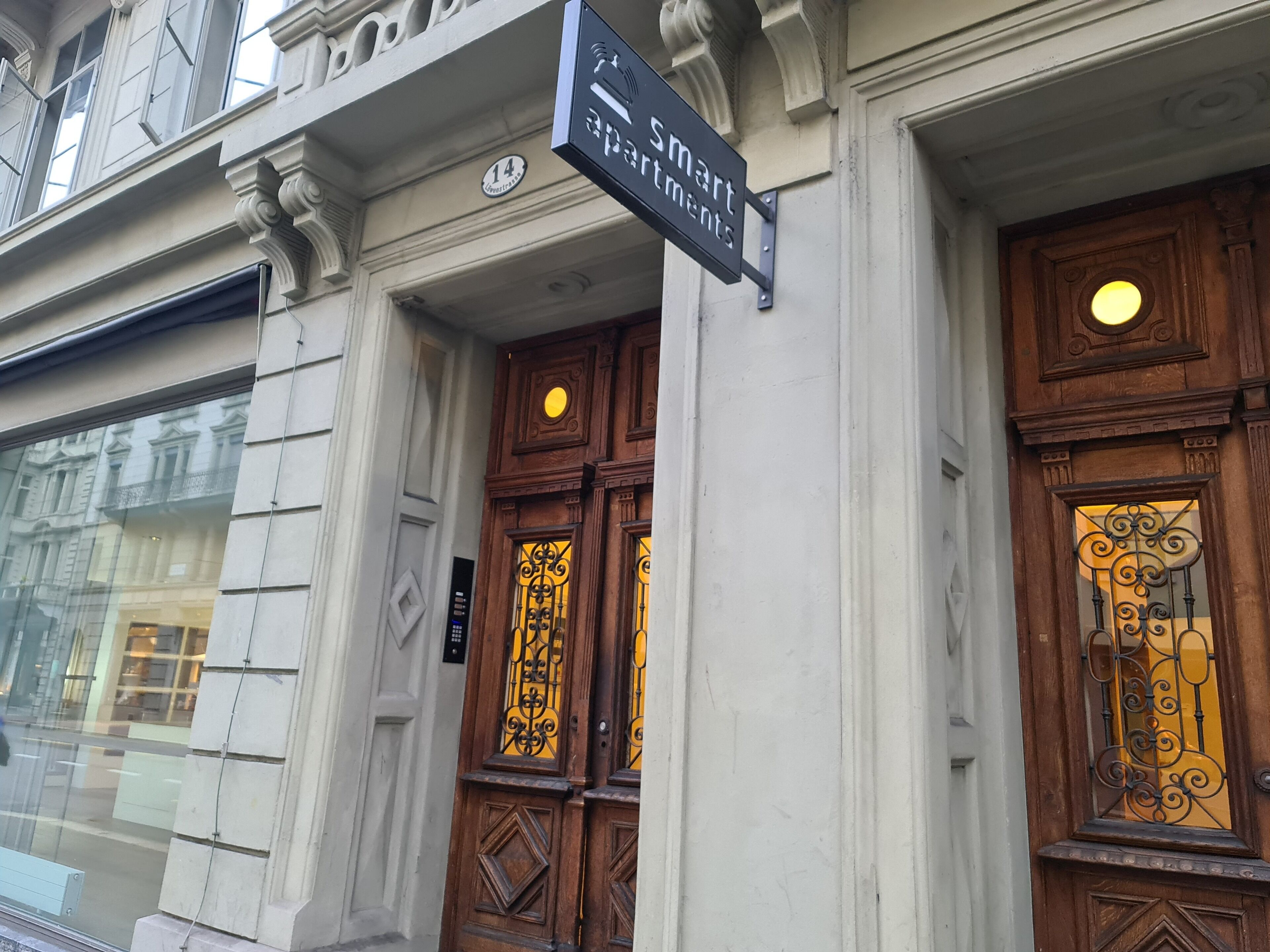 En bygningseingang med et skilt, der viser "Smart Apartments", og nummeret "14" over døren.