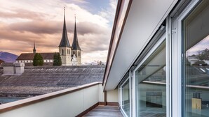 A balcony with a view of a church and mountains. - Top city center Lion Monument (Lucerne)