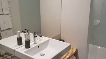 A bathroom with a white sink, two faucets, and a wooden towel rack.