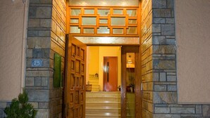 L'ingresso di un hotel con facciata in pietra, porte in legno e un tappeto di benvenuto.