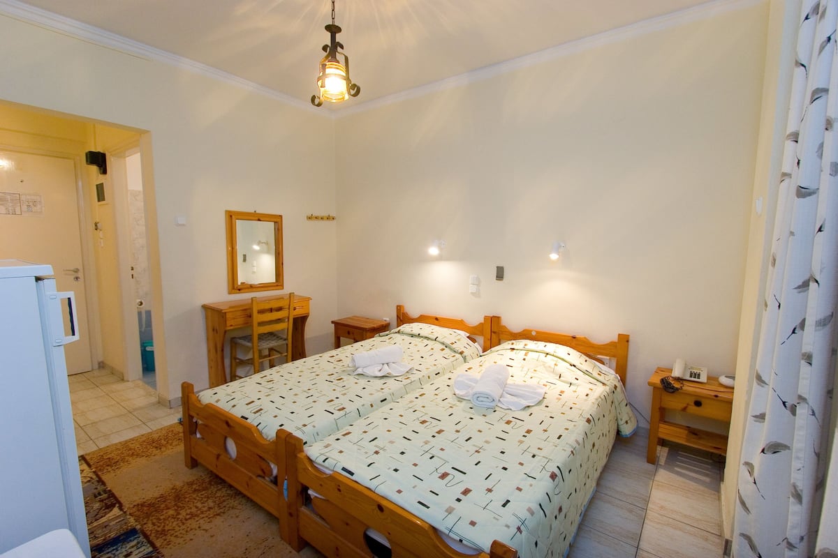 Ein Schlafzimmer mit zwei hölzernen Betten, einem Schreibtisch aus Holz, einem Spiegel und einem Nachttisch.