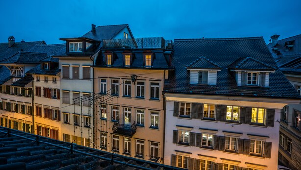 Une rangée de bâtiments européens traditionnels, à plusieurs étages, dotés de balcons et de volets de fenêtre uniformes.