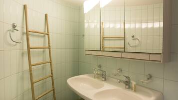 Un baño con un lavamanos blanco, un espejo y una escalera de madera.