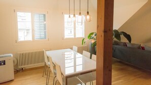 Une pièce lumineuse comprenant une table à manger, des chaises, un radiateur et une plante.