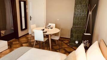 A hotel room with a bed, a dining table with chairs, a green cabinet, and a mirror.