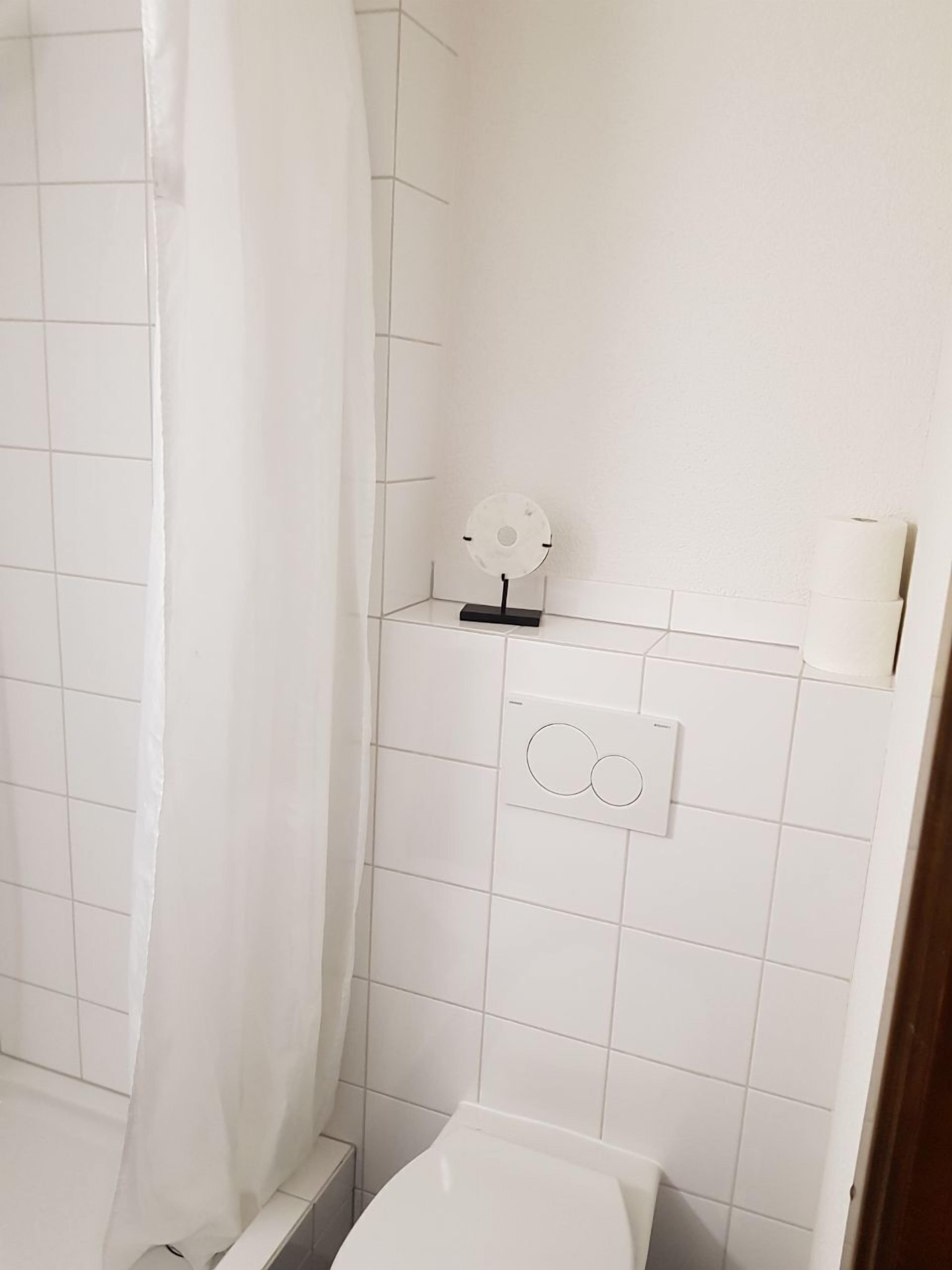 Ein Badezimmer mit Dusche, Toilette und Handtuchspender.