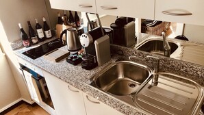 Una cocina moderna con encimeras de granito, electrodomésticos de acero inoxidable y una botellera con varias botellas.