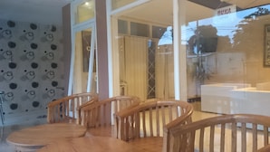 Un restaurante con sillas y mesas de madera, una puerta de vidrio y un cartel que indica que está abierto.
