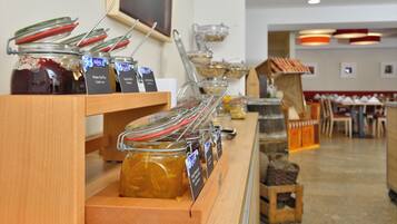 A buffet setup with various food items in jars and bowls, wooden serving boards, and a seating area in the background.