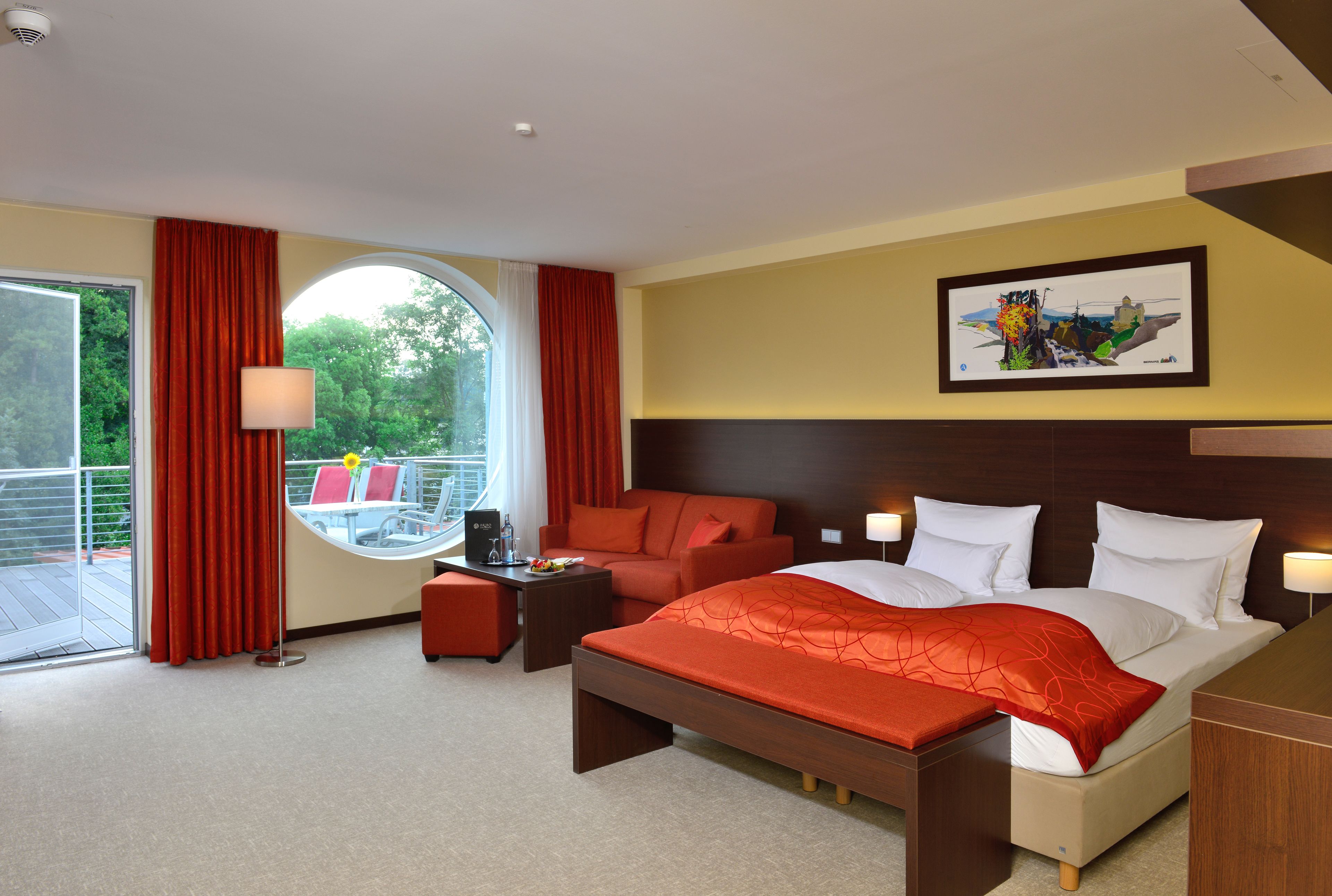 A hotel room with a bed, a desk, a chair, and a view of the outdoors.