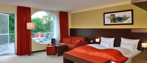 A hotel room with a bed, a desk, a chair, and a view of the outdoors.
