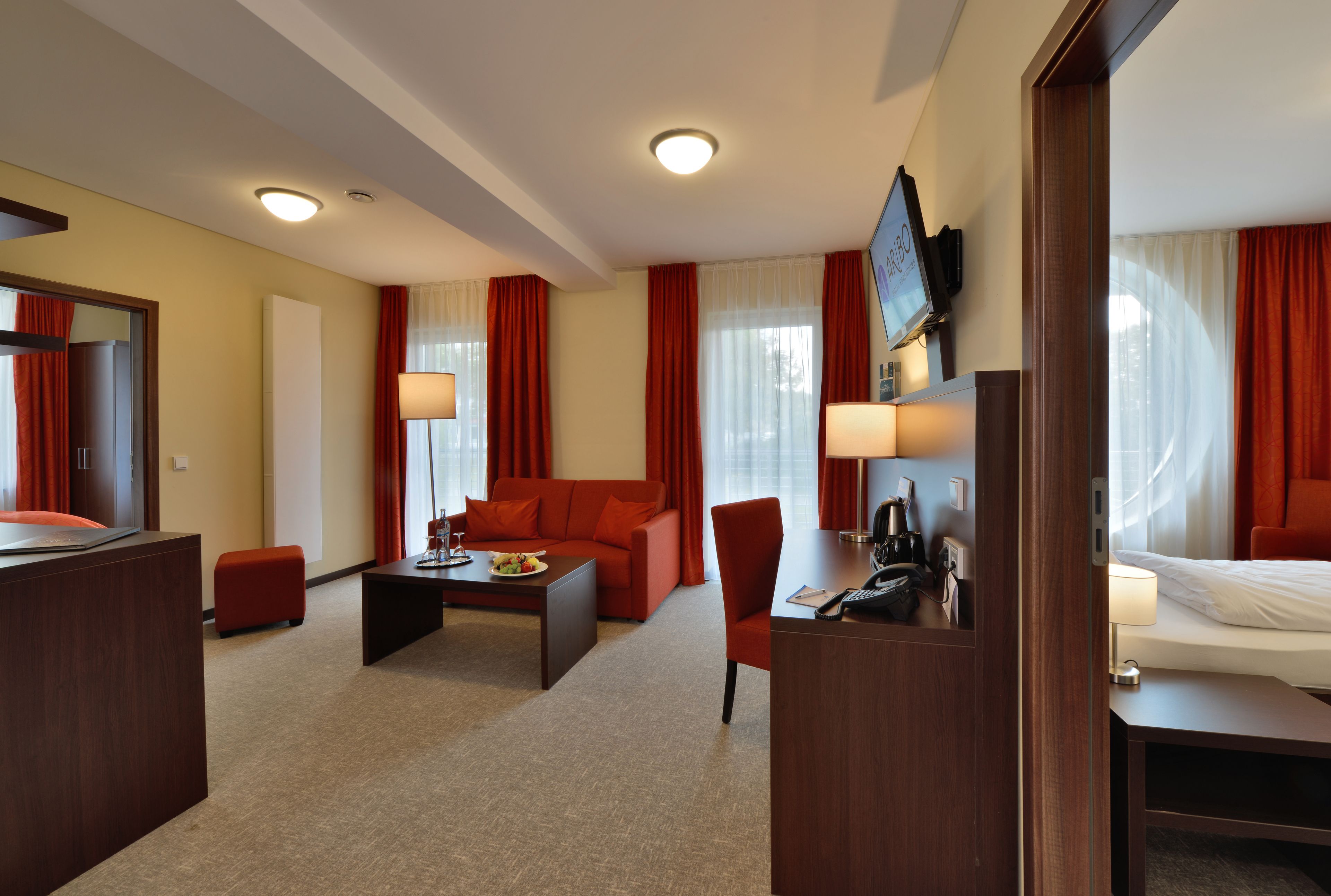 Una habitación de hotel con una cama, un escritorio, un sofá y un televisor.